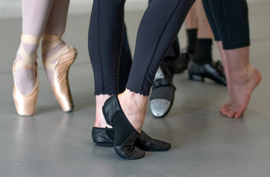 Pointe shoes, jazz shoes and tap shoes on a grey marley floor