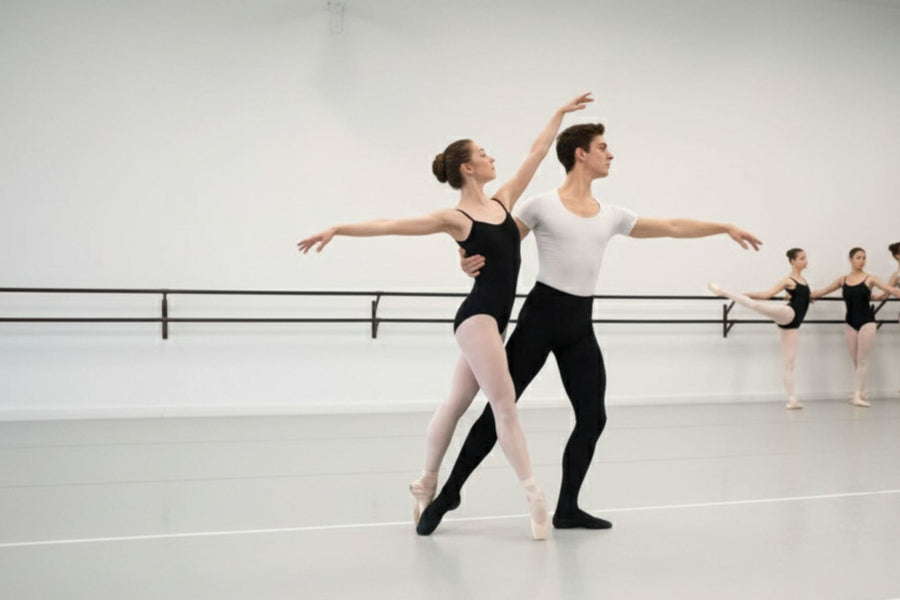 Two dancers rehearsing in a bright studio with a light grey marley floor